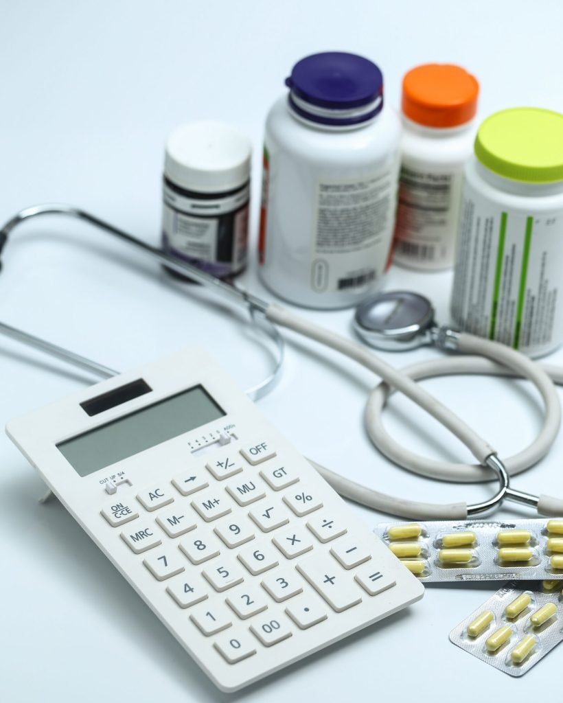 calculator, stethoscope and medicine bottles on white background